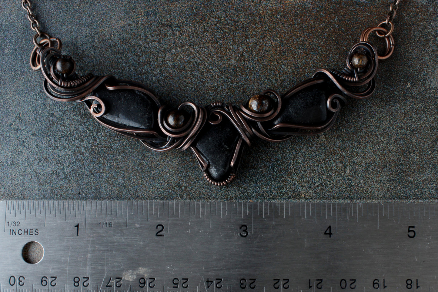 Necklace on a textured surface with a ruler for scale.
