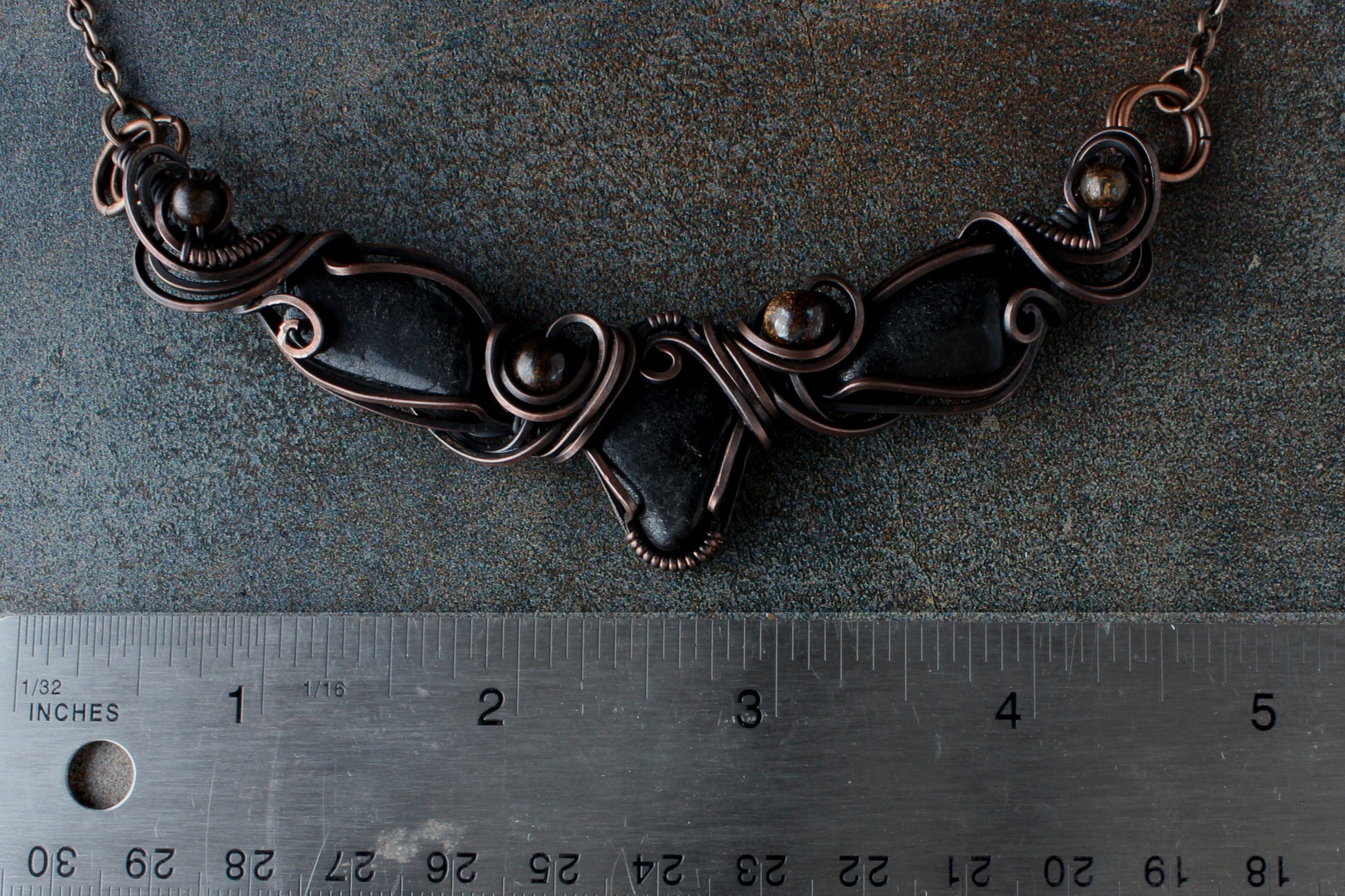 Necklace on a textured surface with a ruler for scale.