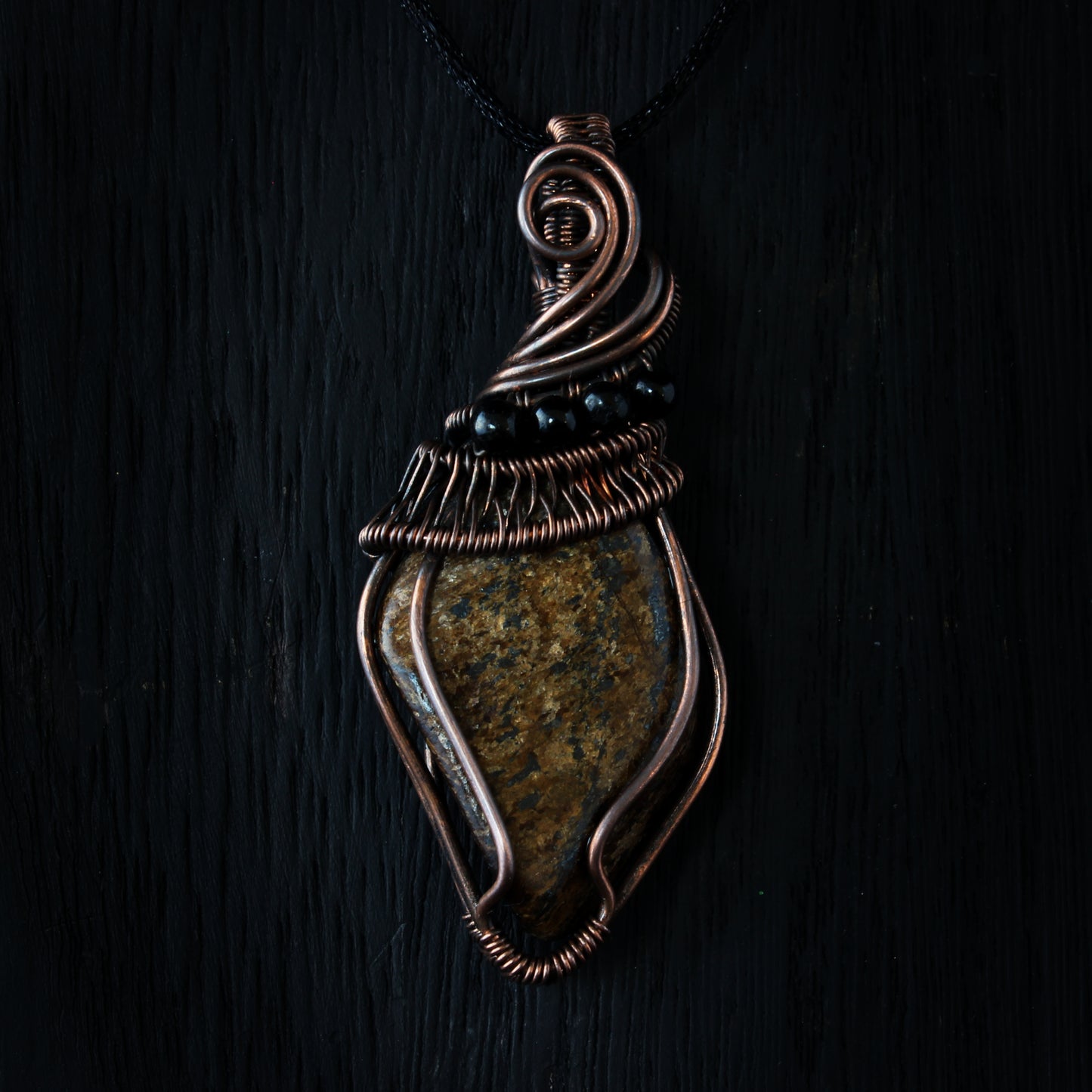 Decorative pendant with stone and wirework on a dark background