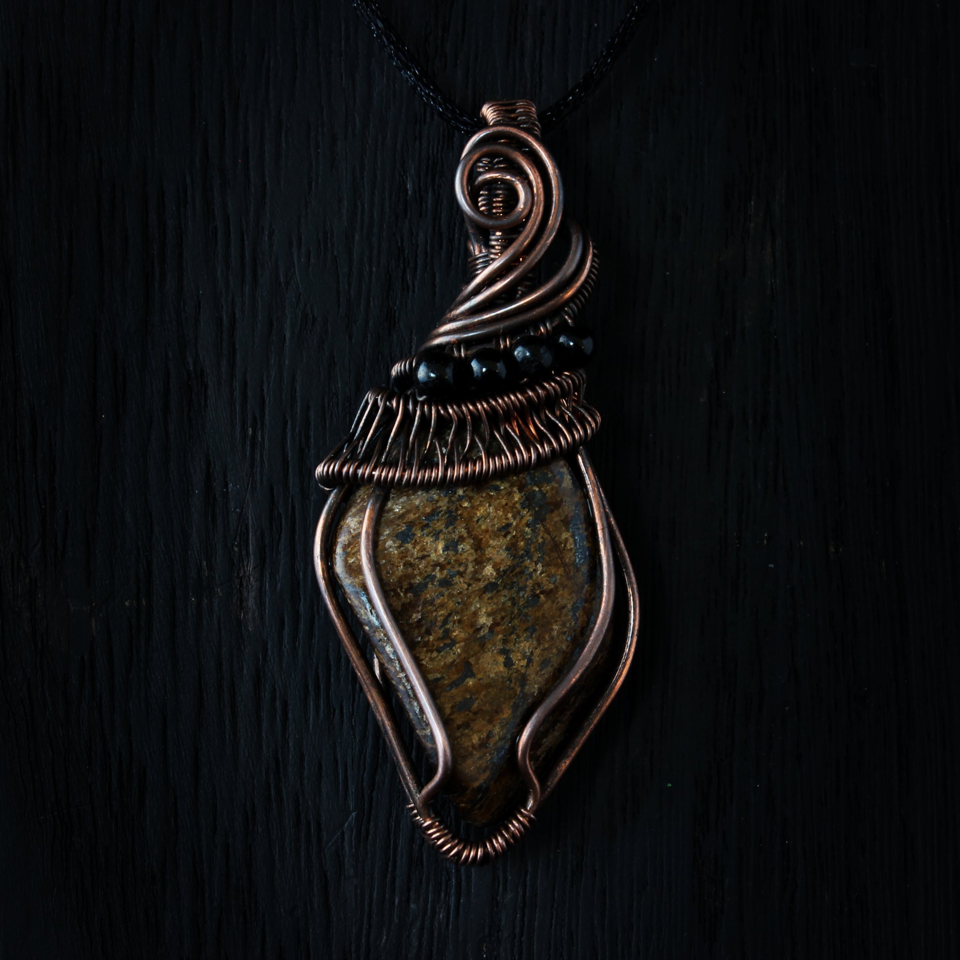 Decorative pendant with stone and wirework on a dark background